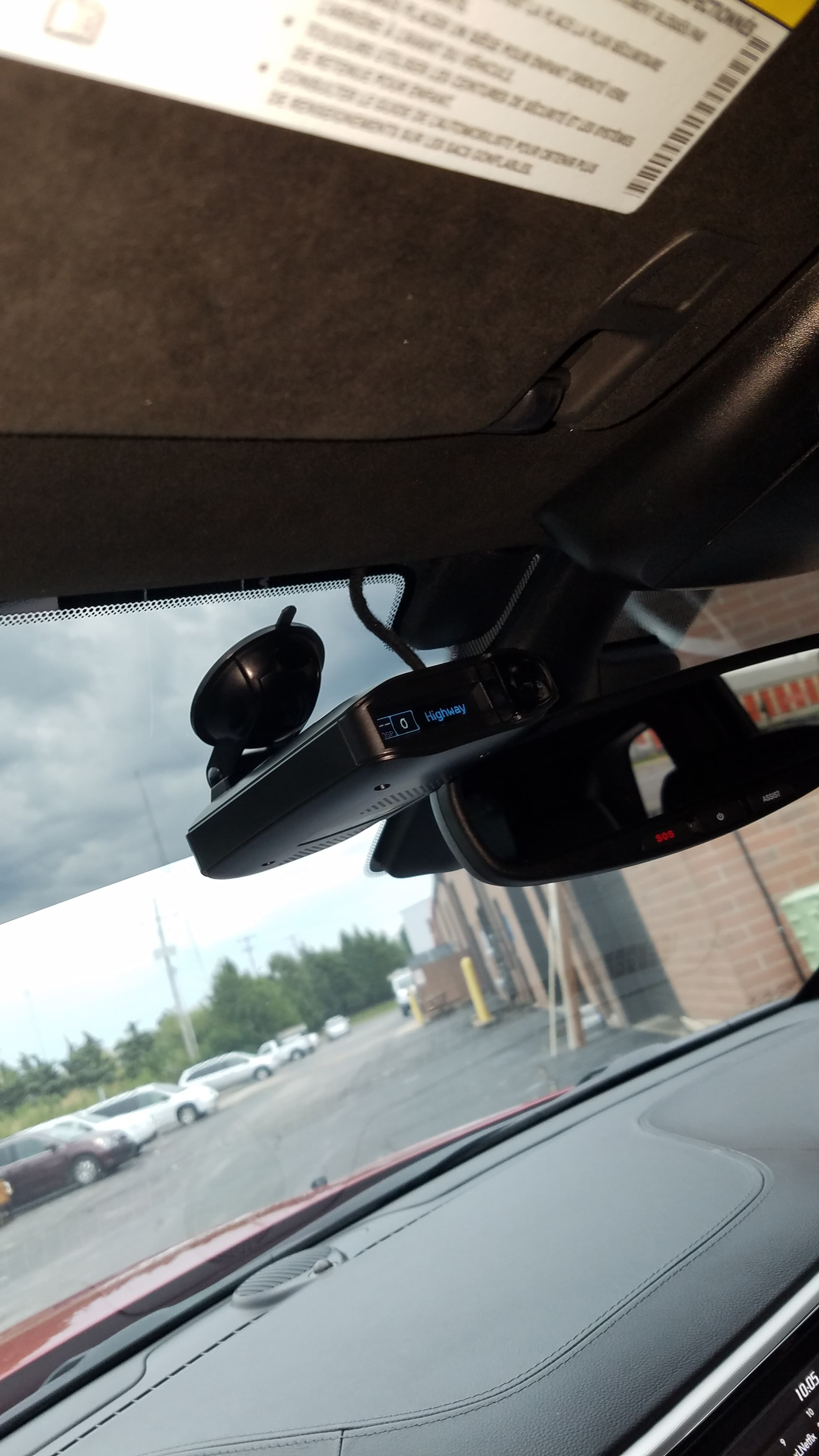 Radar detector mounted high on a windshield displaying Highway mode.