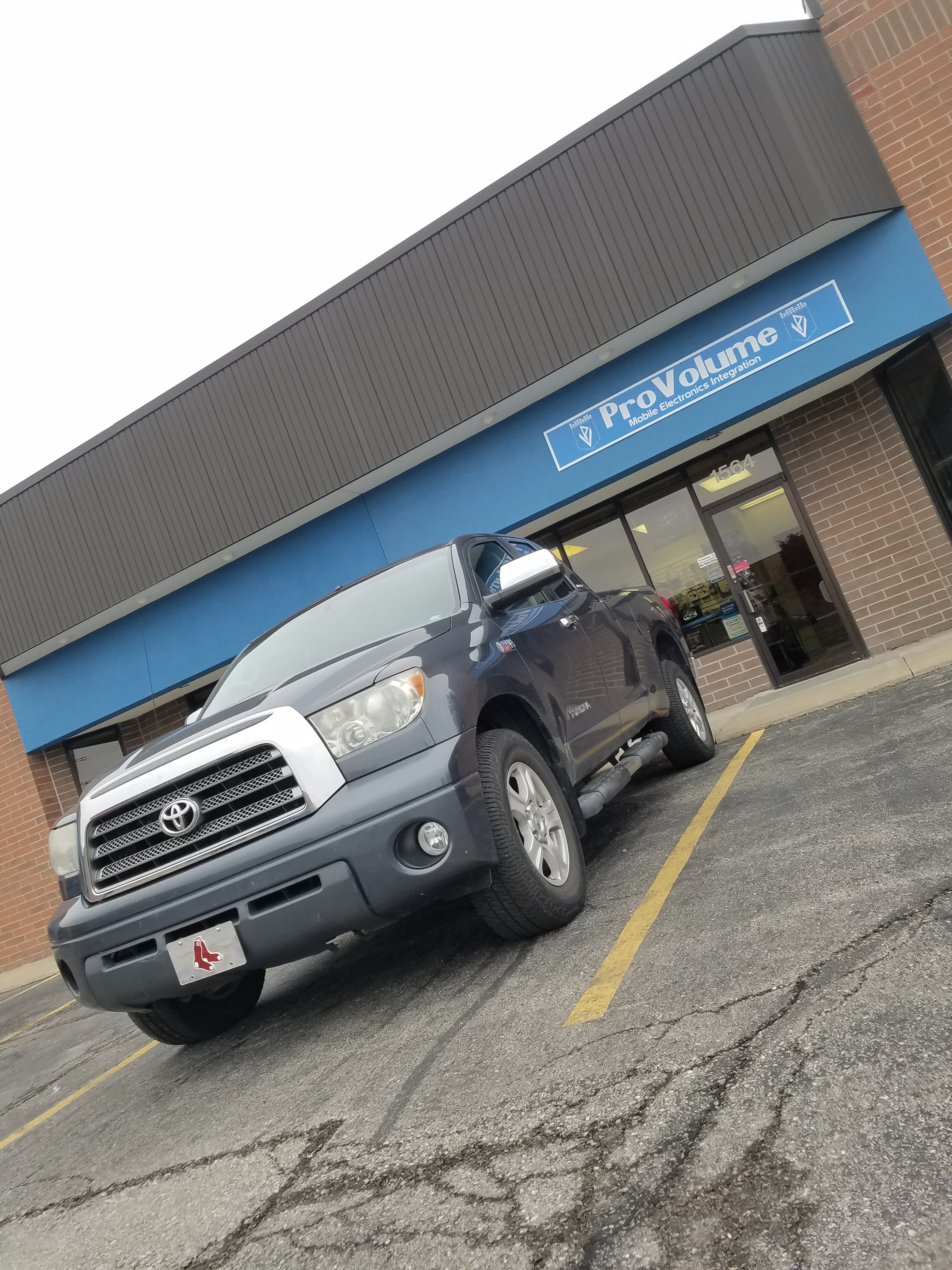 Dark grey Toyota Tundra truck parked in front of a ProVolume mobile electronics store.