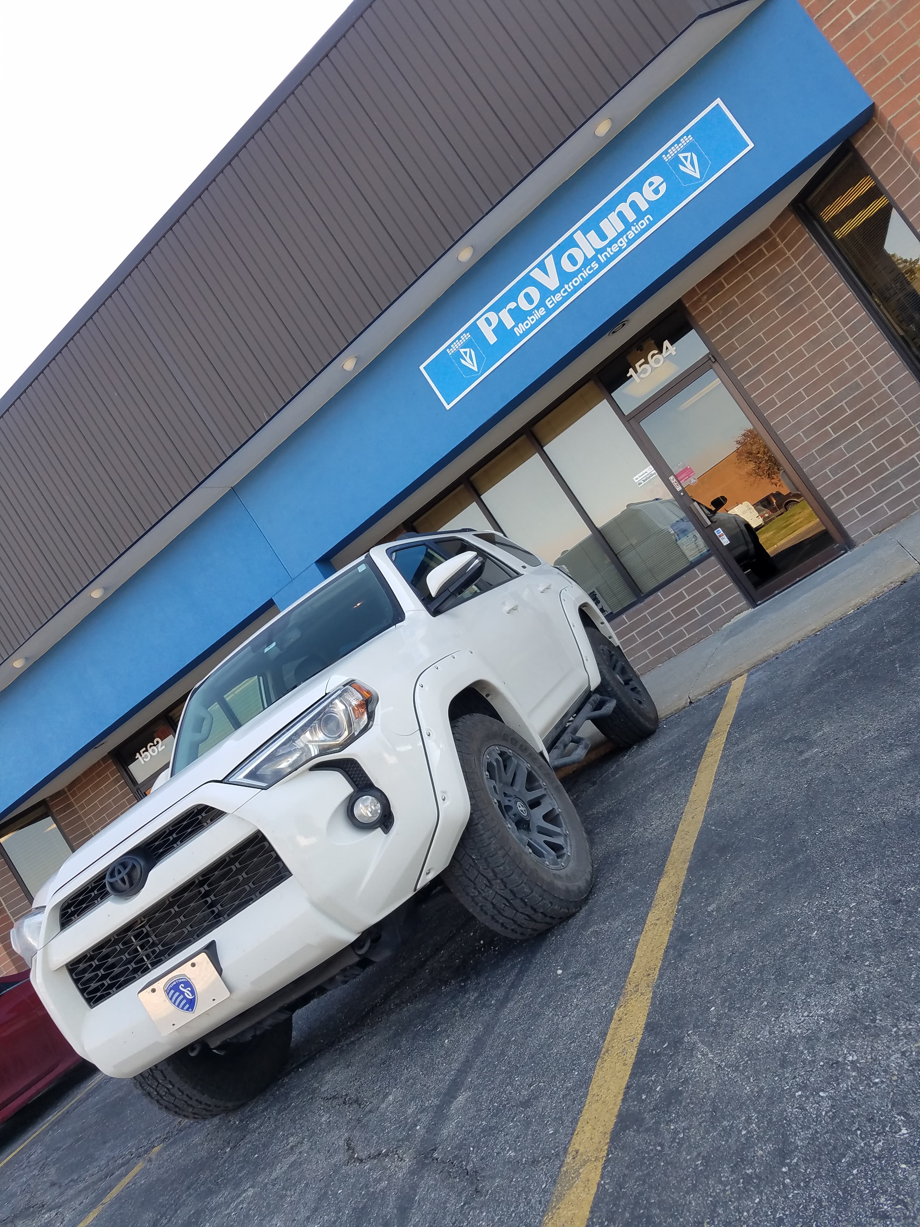 White Toyota 4Runner parked in front of a ProVolume Mobile Electronics Integration storefront.
