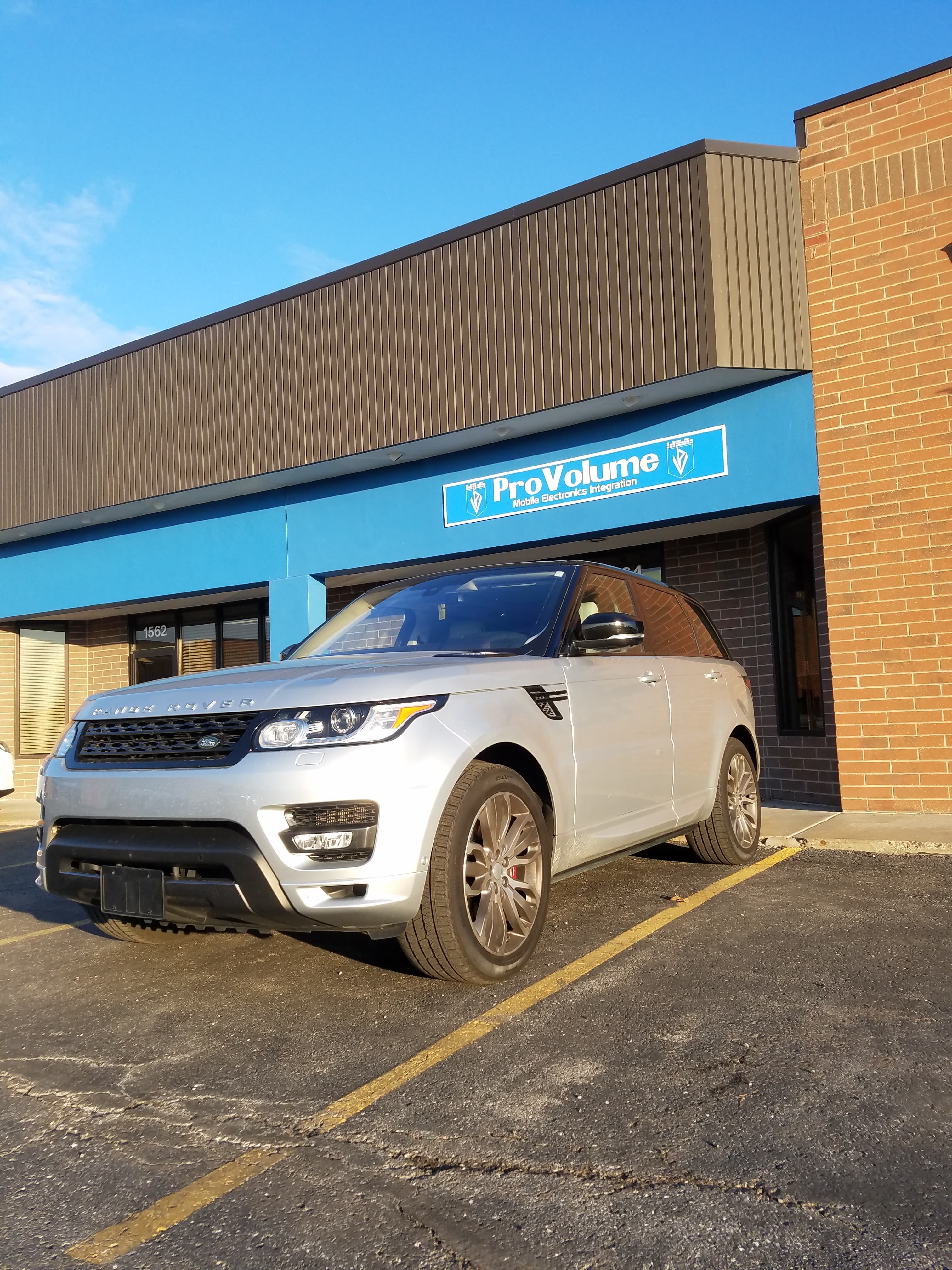 Silver Range Rover Sport parked in front of a ProVolume mobile electronics integration shop.