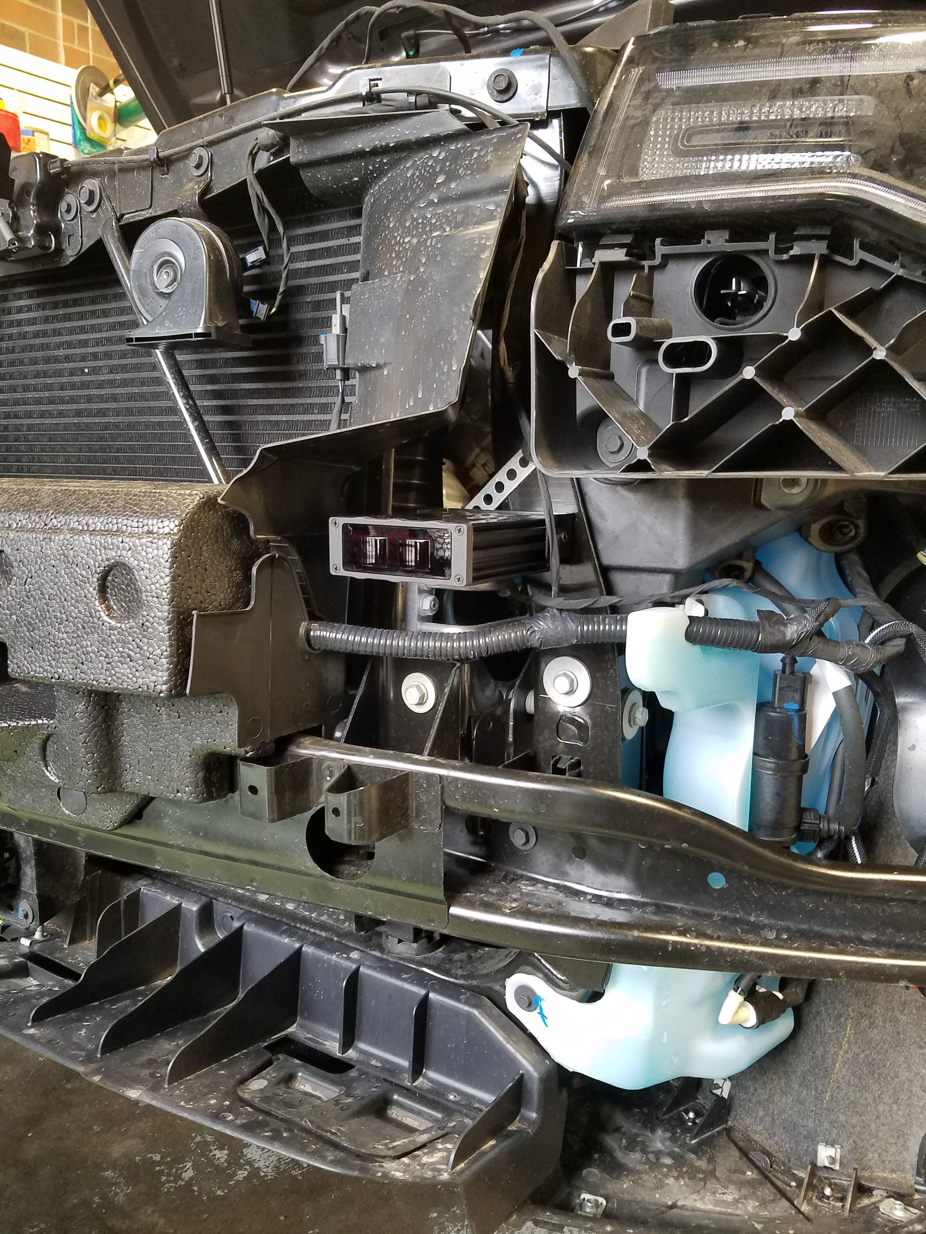 Exposed internal front-end components of a car with the bumper and grille assembly removed.
