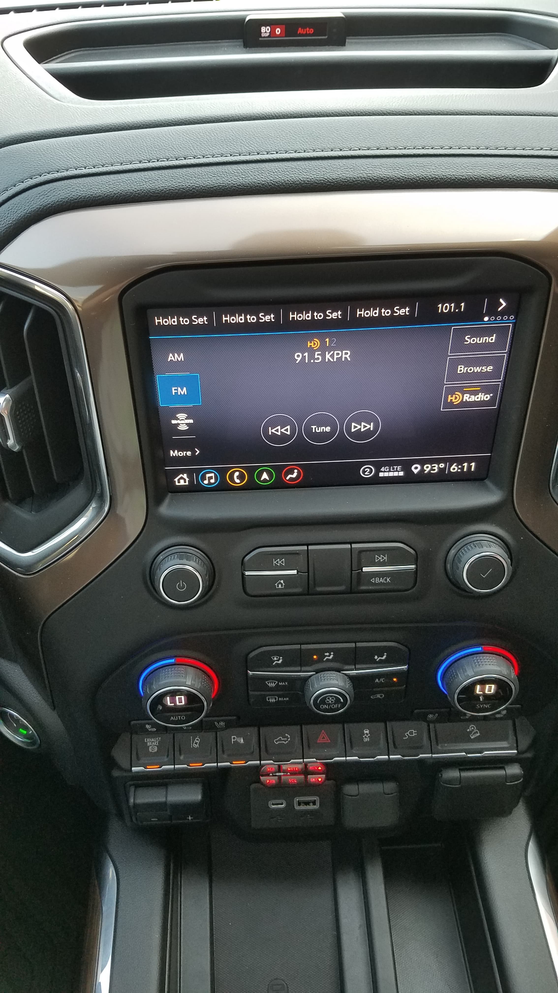 Vehicle center console featuring a touchscreen infotainment system, climate control dials, and various functional buttons.