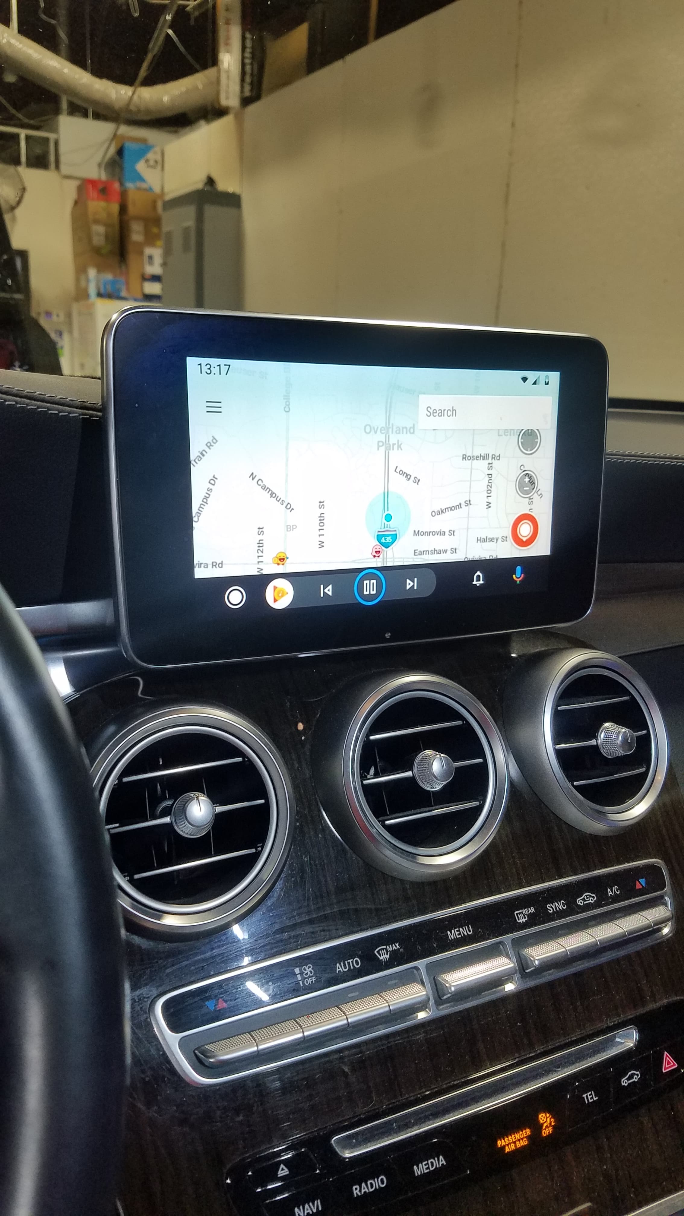 Infotainment screen displaying a map above three circular air vents in a car's dashboard.