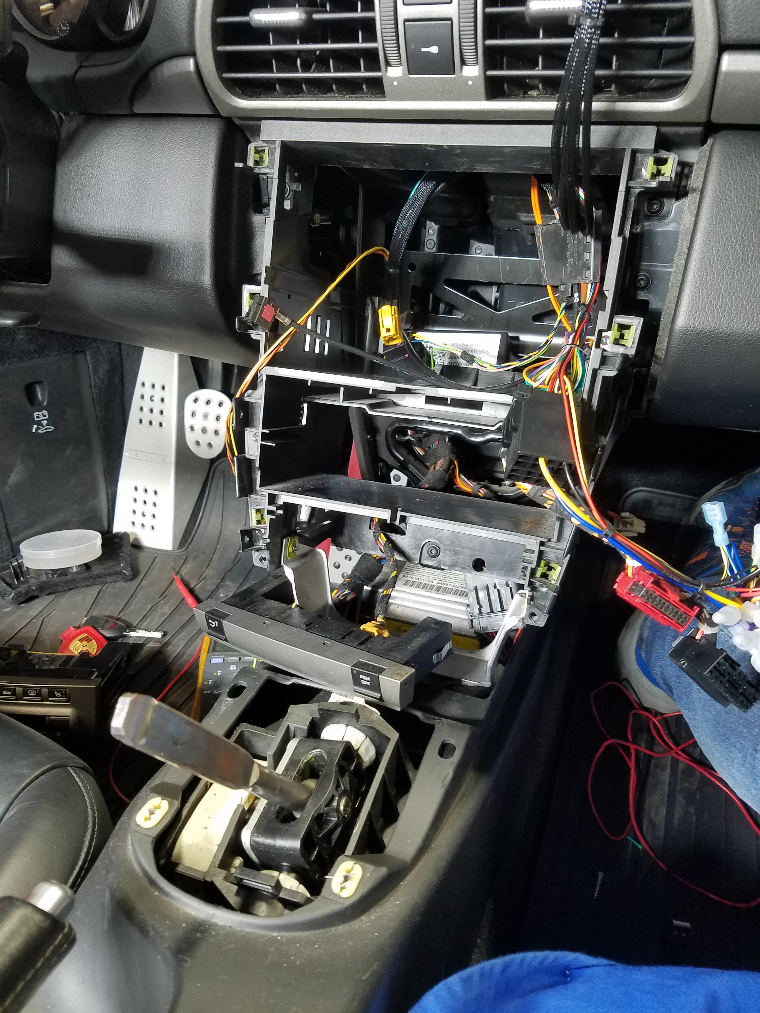 Disassembled car dashboard with exposed multicolored wiring and removed radio unit during an electrical repair.