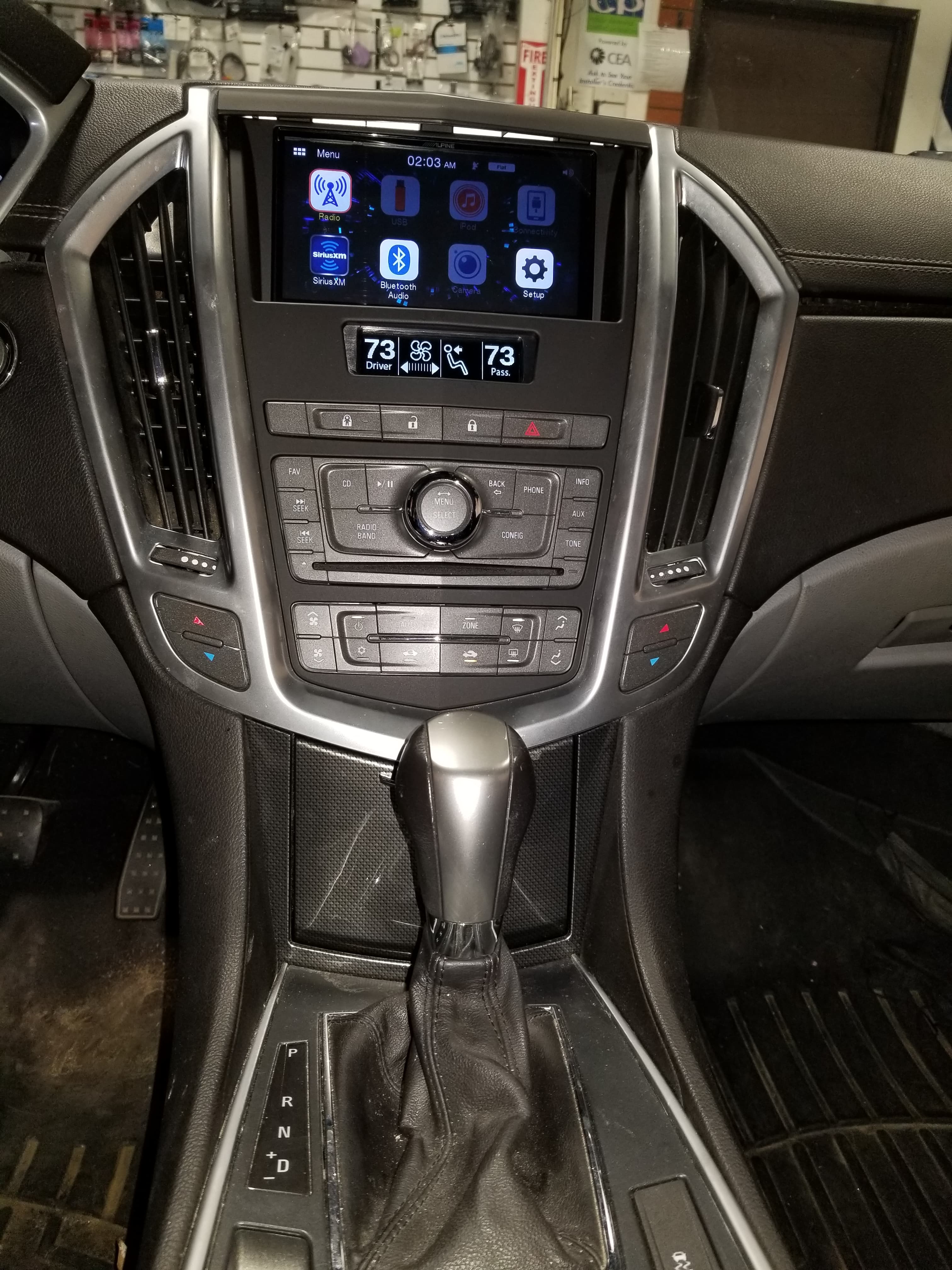 Modern car dashboard with a touchscreen display, dual-zone climate controls, and a gear shifter.