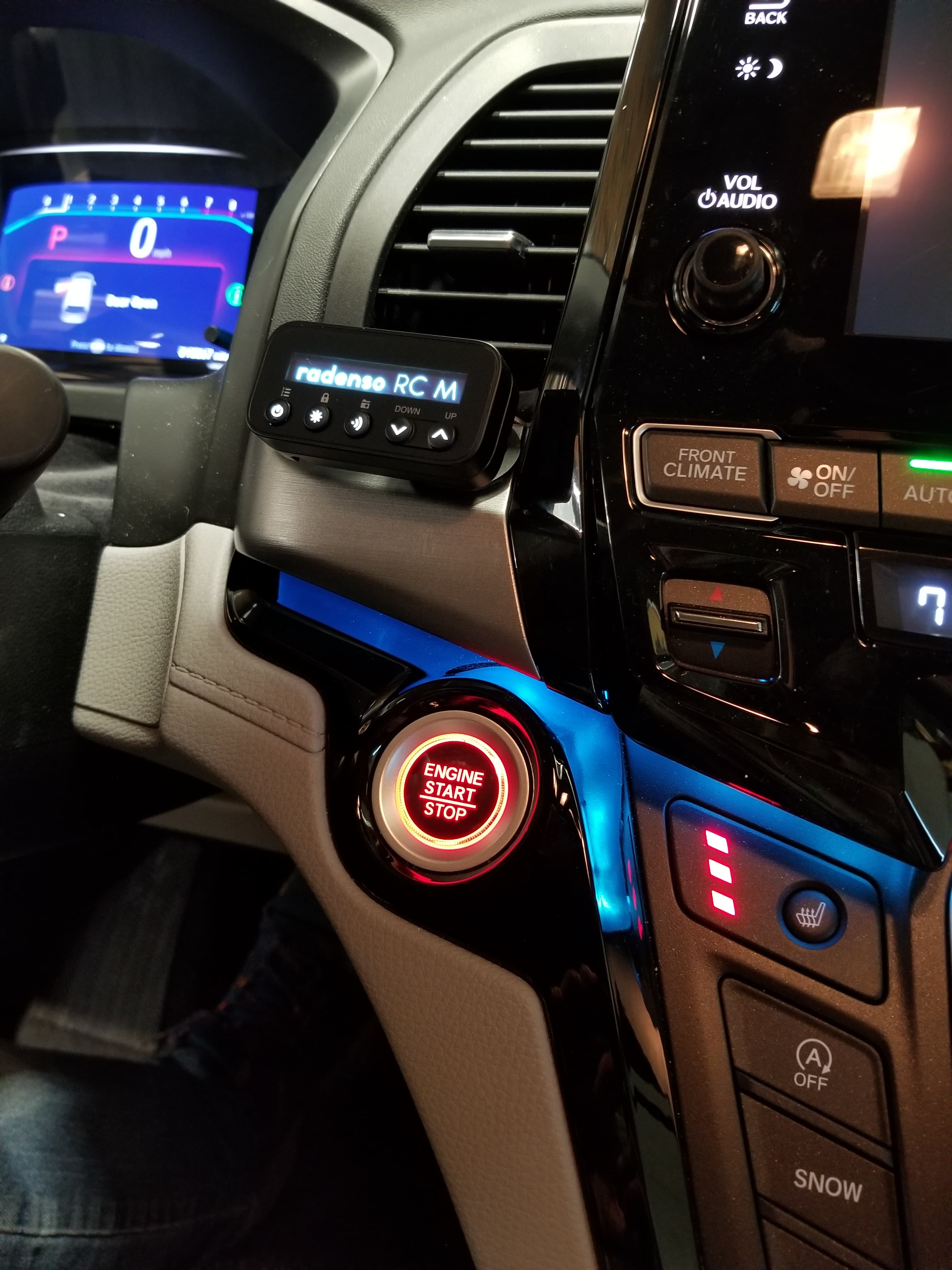 Glowing red engine start button and Radenso radar detector on a car's dashboard.