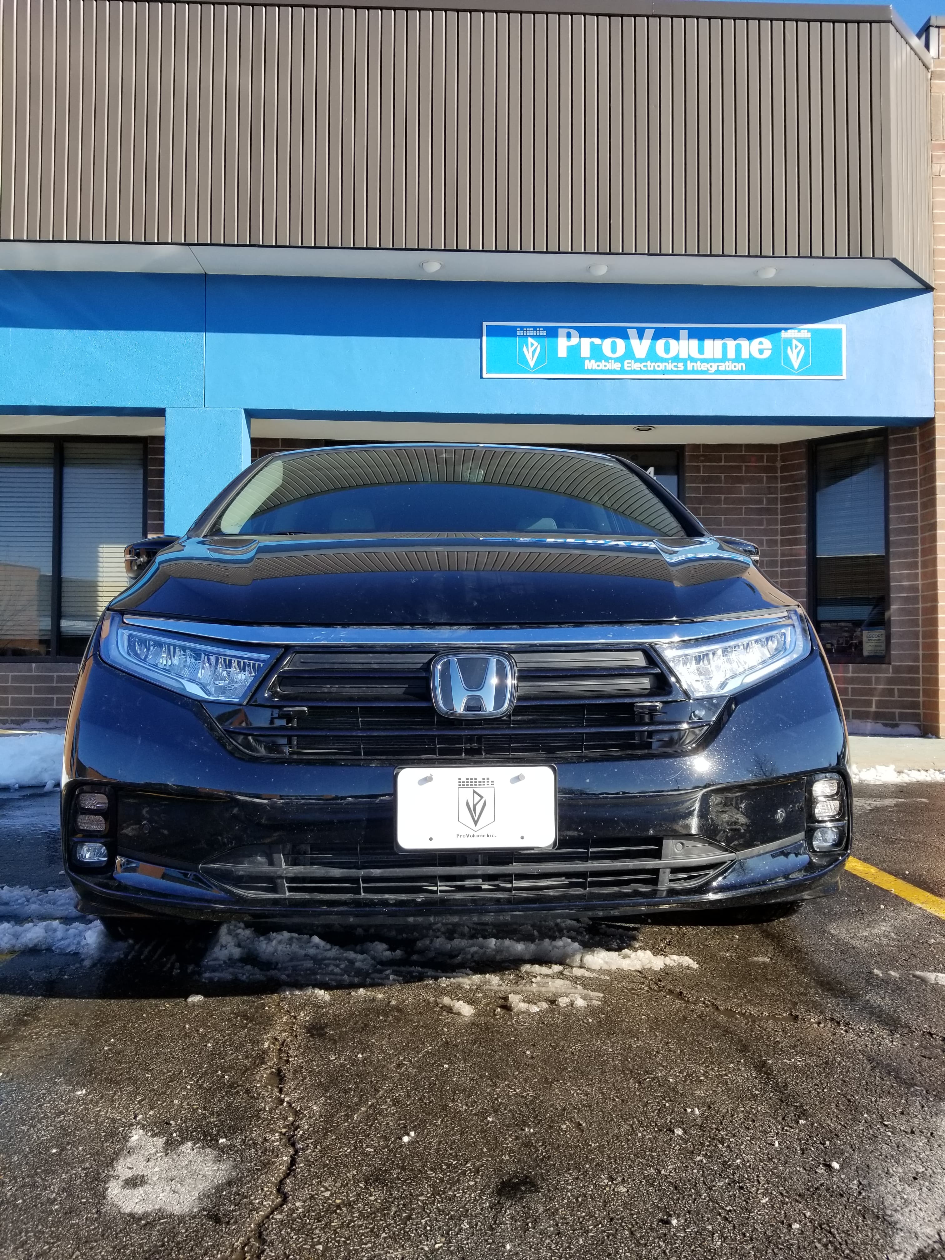 Front view of a black Honda SUV parked outside ProVolume Mobile Electronics Integration storefront.