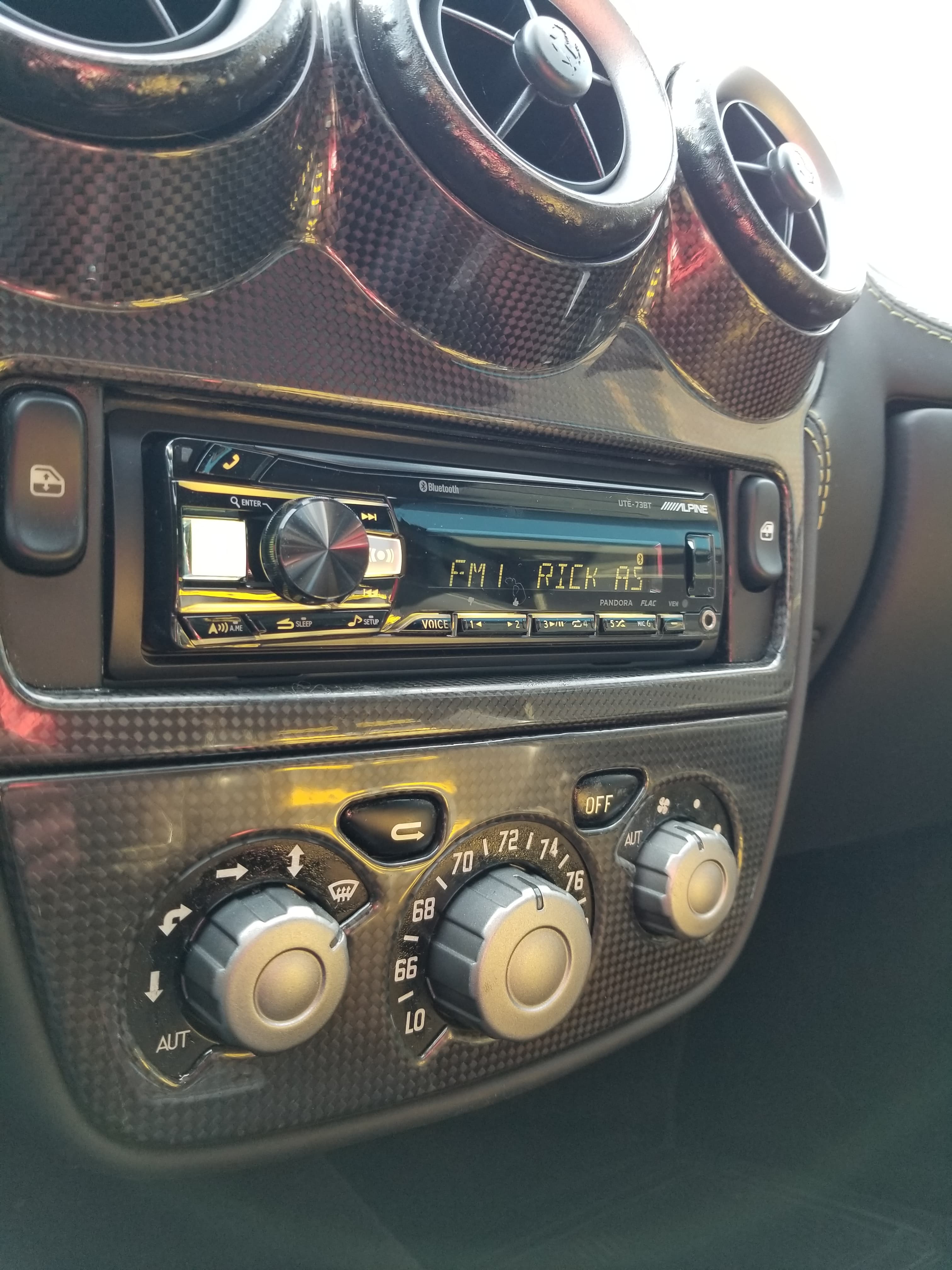 Carbon fiber dashboard featuring an Alpine stereo and control dials