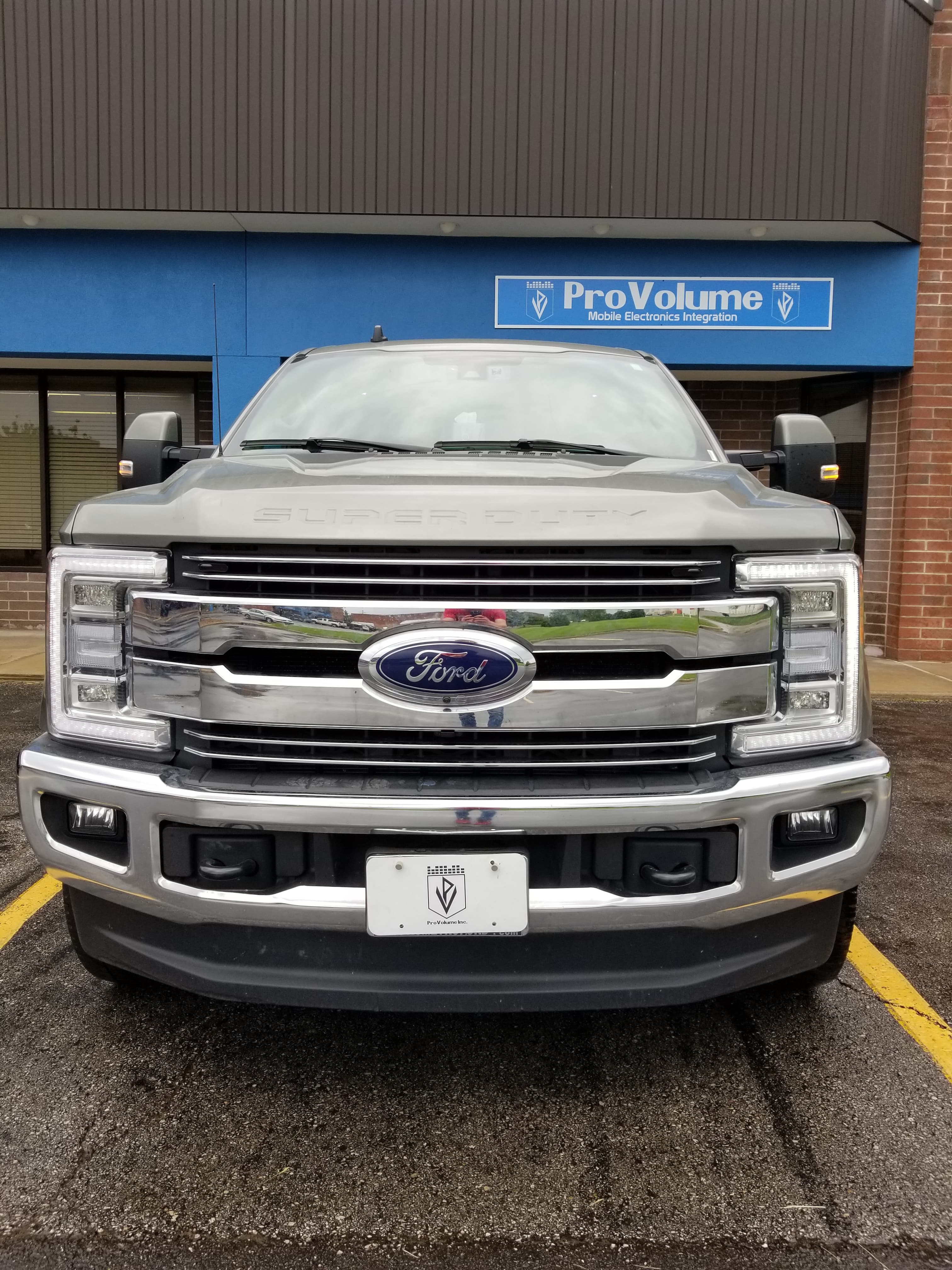 Silver Ford Super Duty truck with a large chrome grille parked in front of ProVolume.