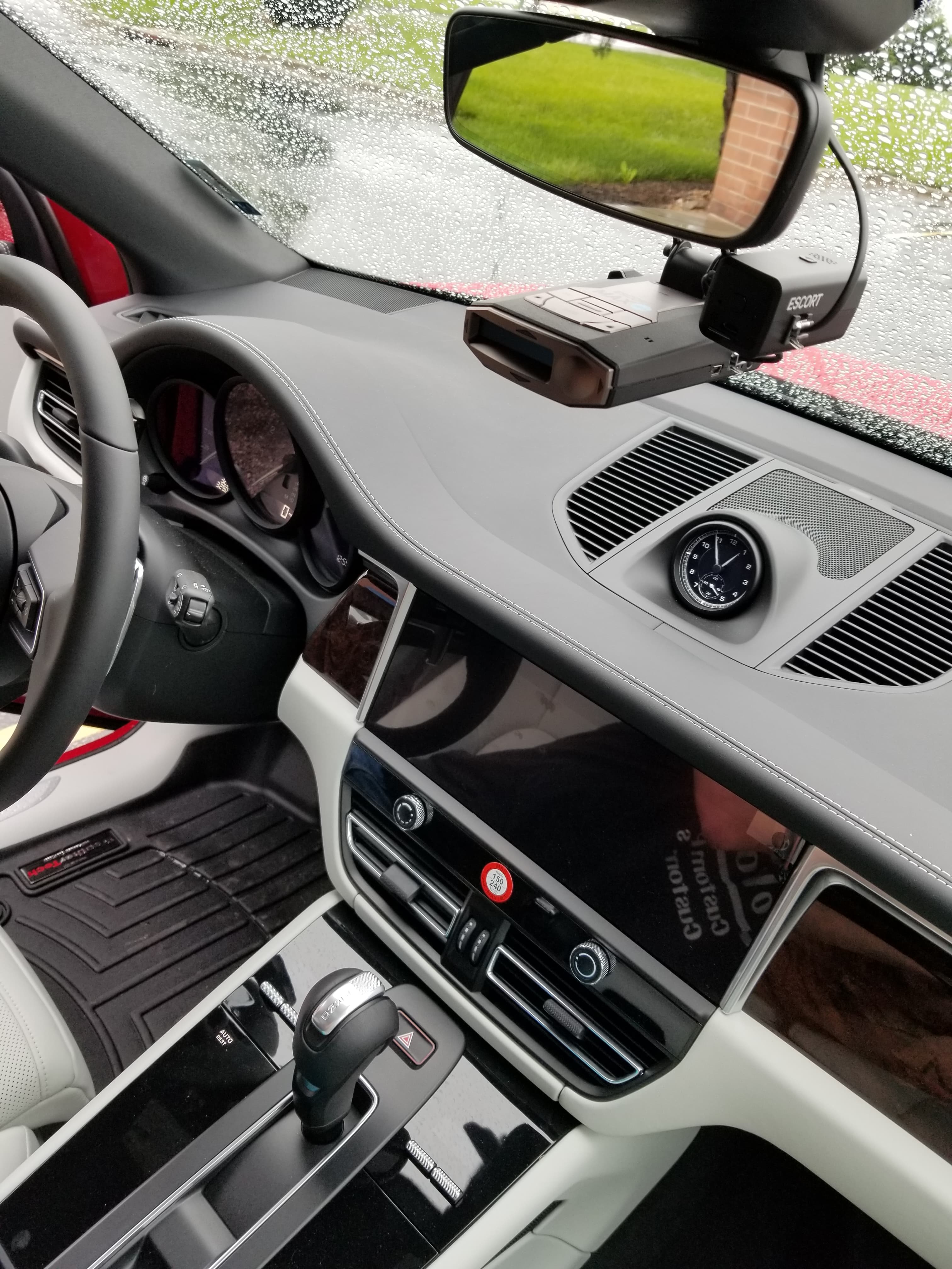 Interior of a luxury car with a leather dashboard, analog clock, and radar detector.