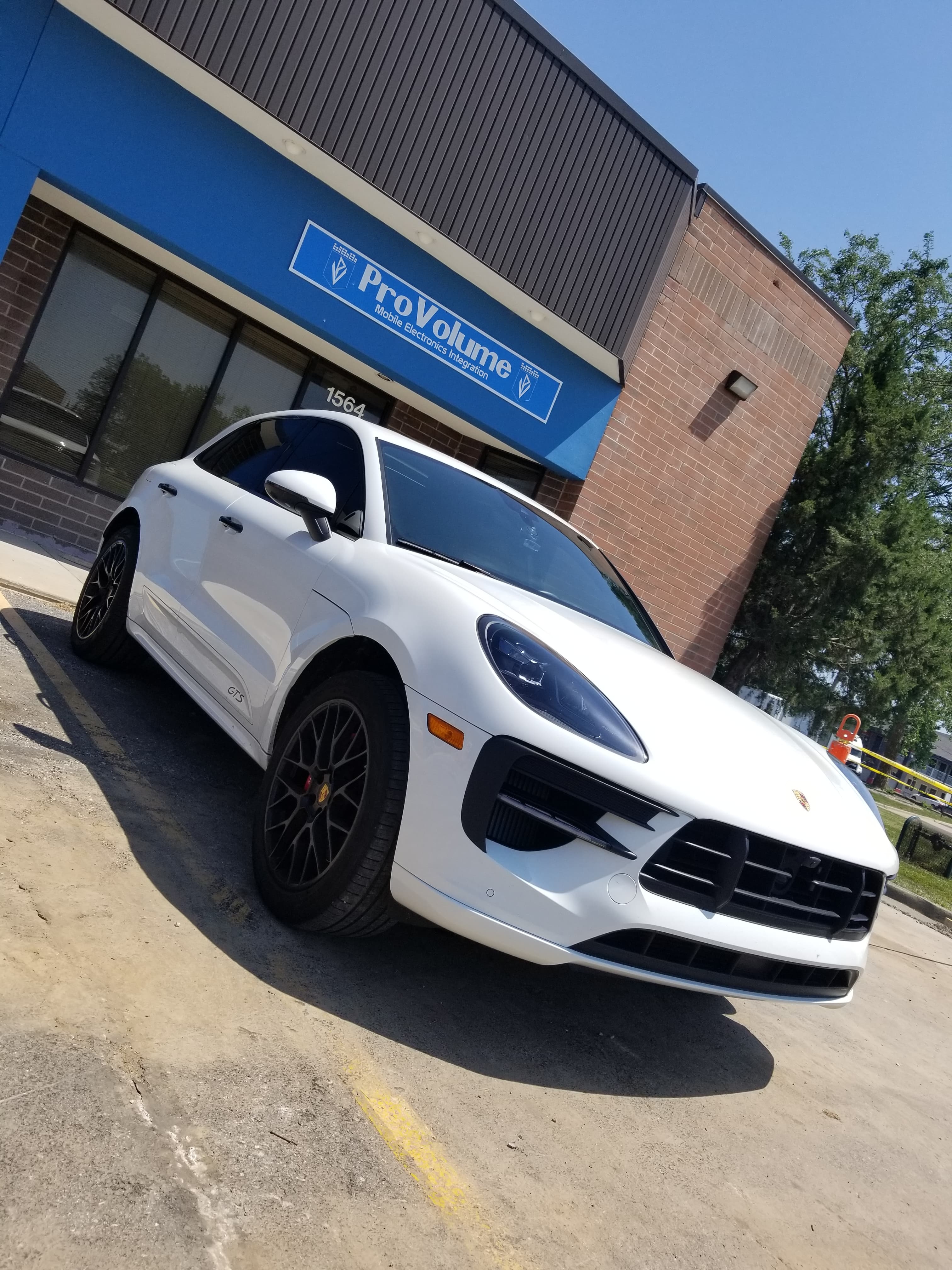 White Porsche Macan GTS parked in front of the ProVolume mobile electronics shop