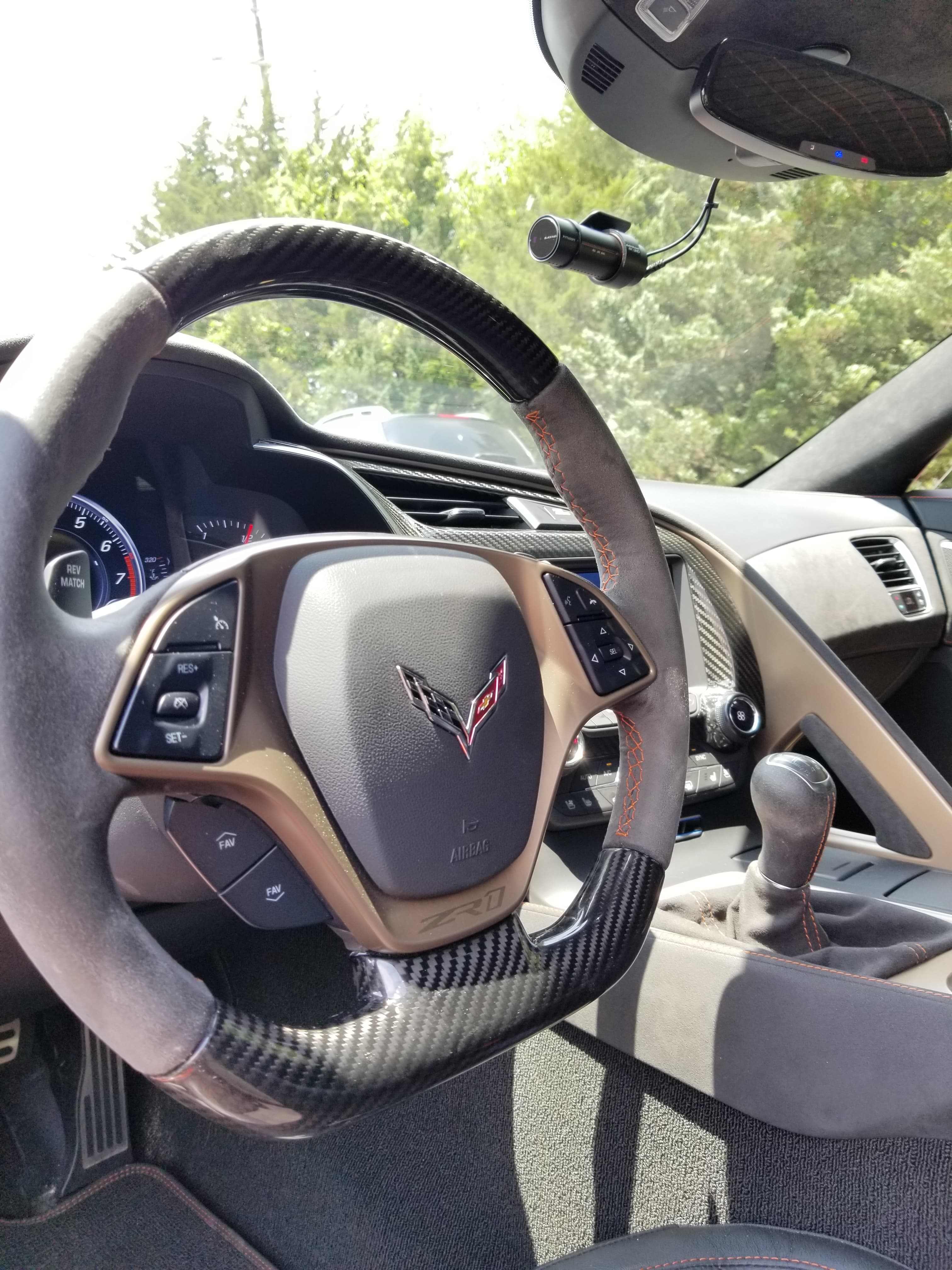 Corvette ZR1 interior with carbon fiber steering wheel, orange stitching, and a manual shifter.