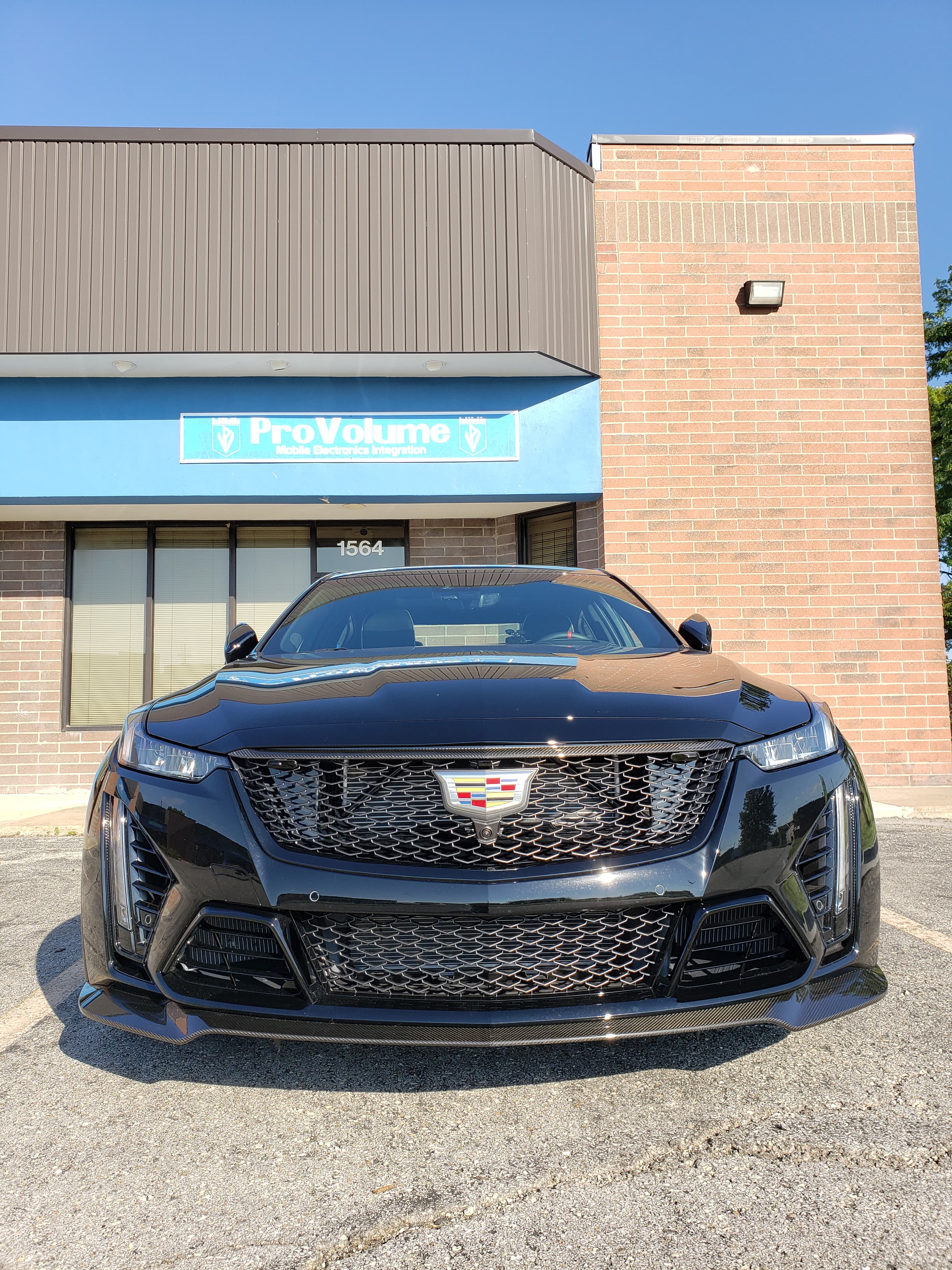 Front view of a black Cadillac parked outside a ProVolume mobile electronics store.