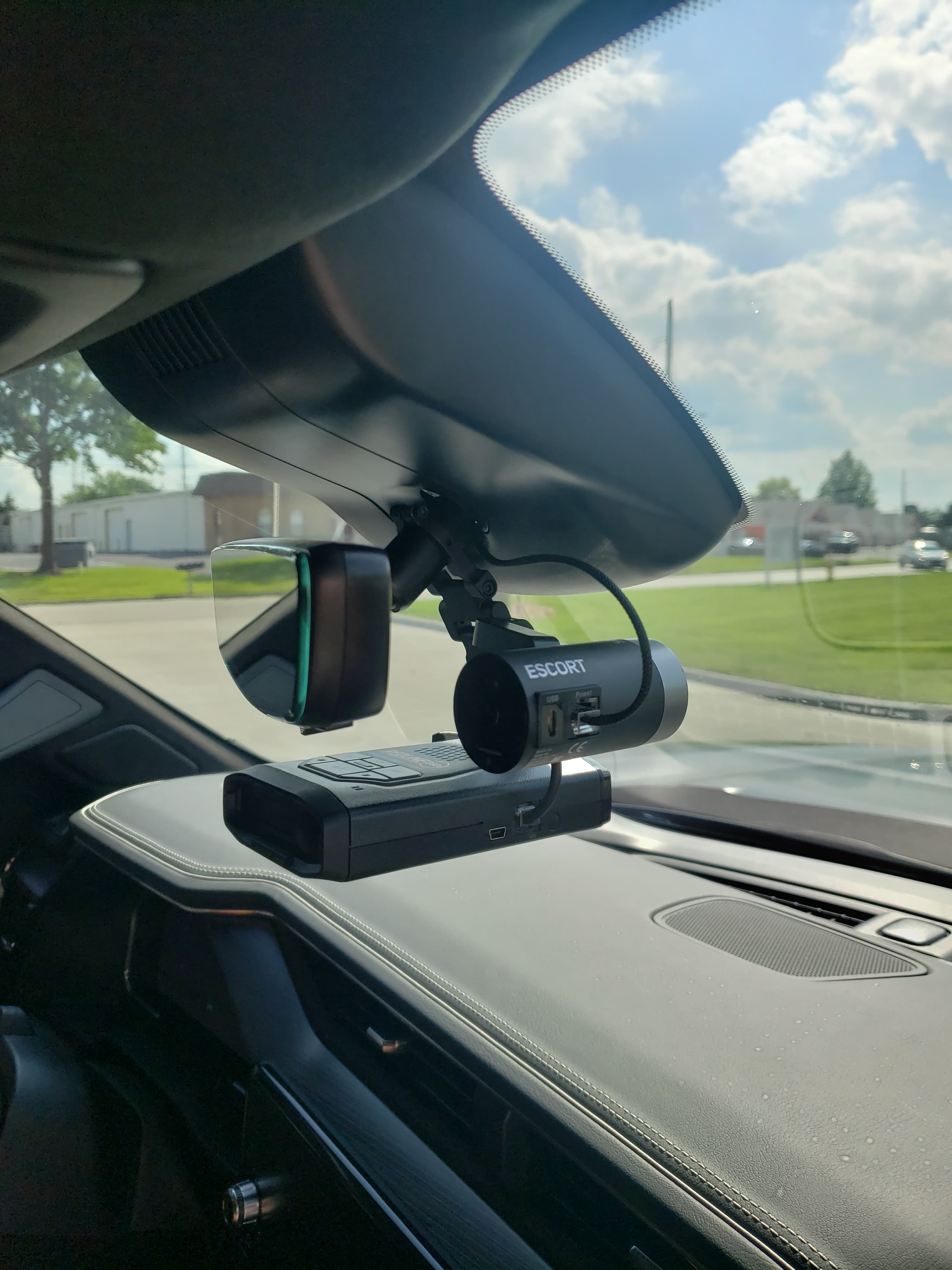 Escort radar detector and dash camera mounted to a car's rearview mirror assembly.